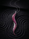 A silver wavy pendant necklace adorned with rows of pink and white gemstones, displayed on a textured black background.